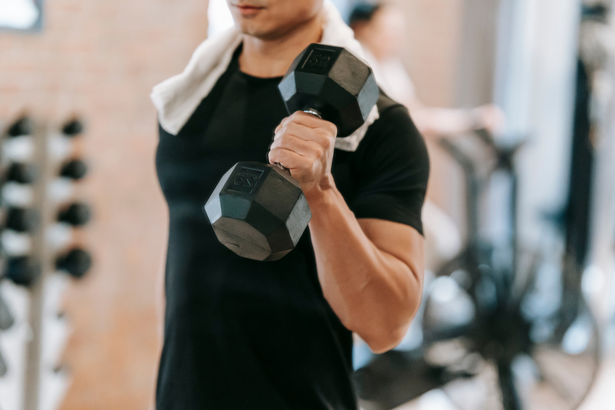 Crop man doing weightlifting workout in gym