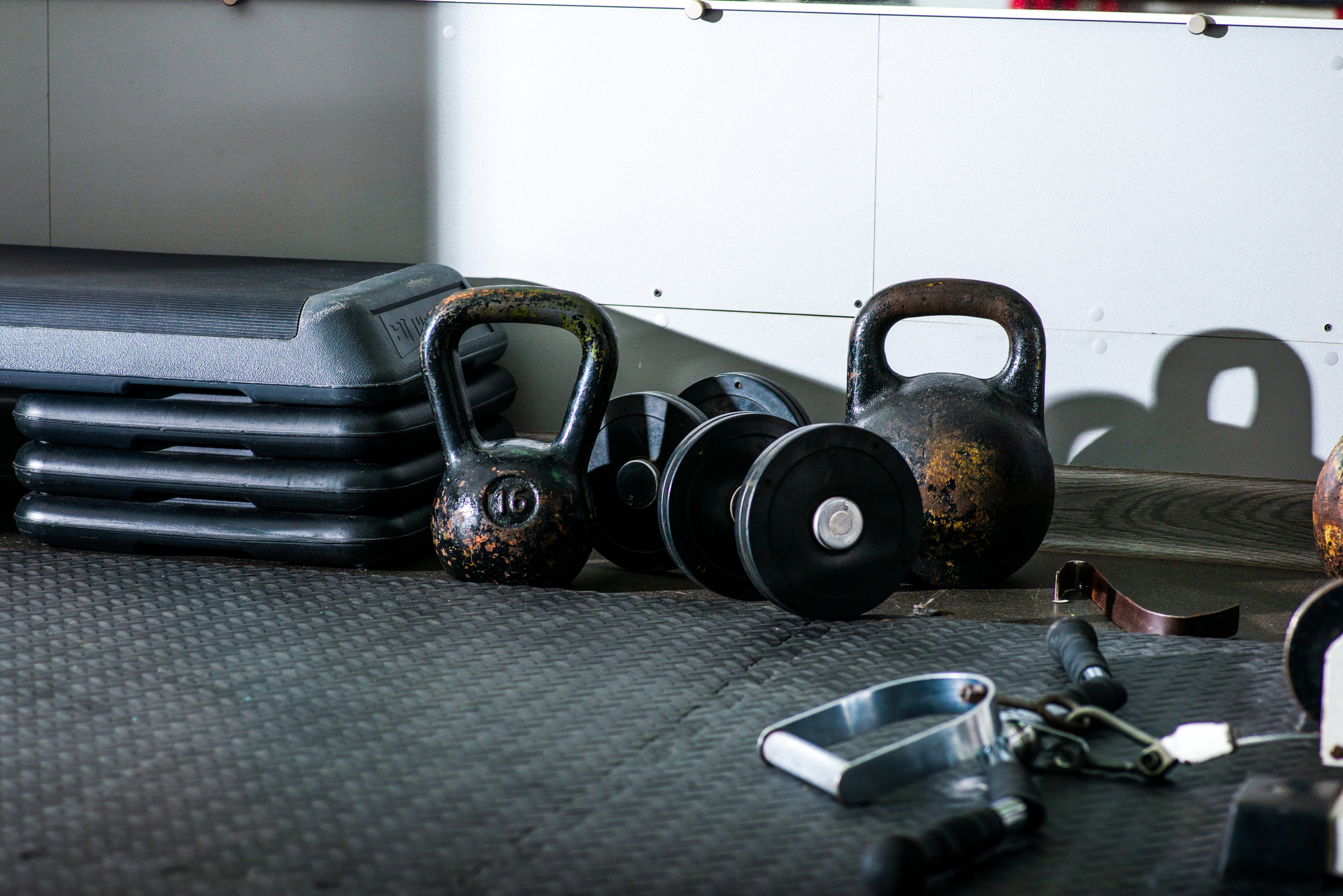 Kettle bells and dumbbells on floor near gym equipment