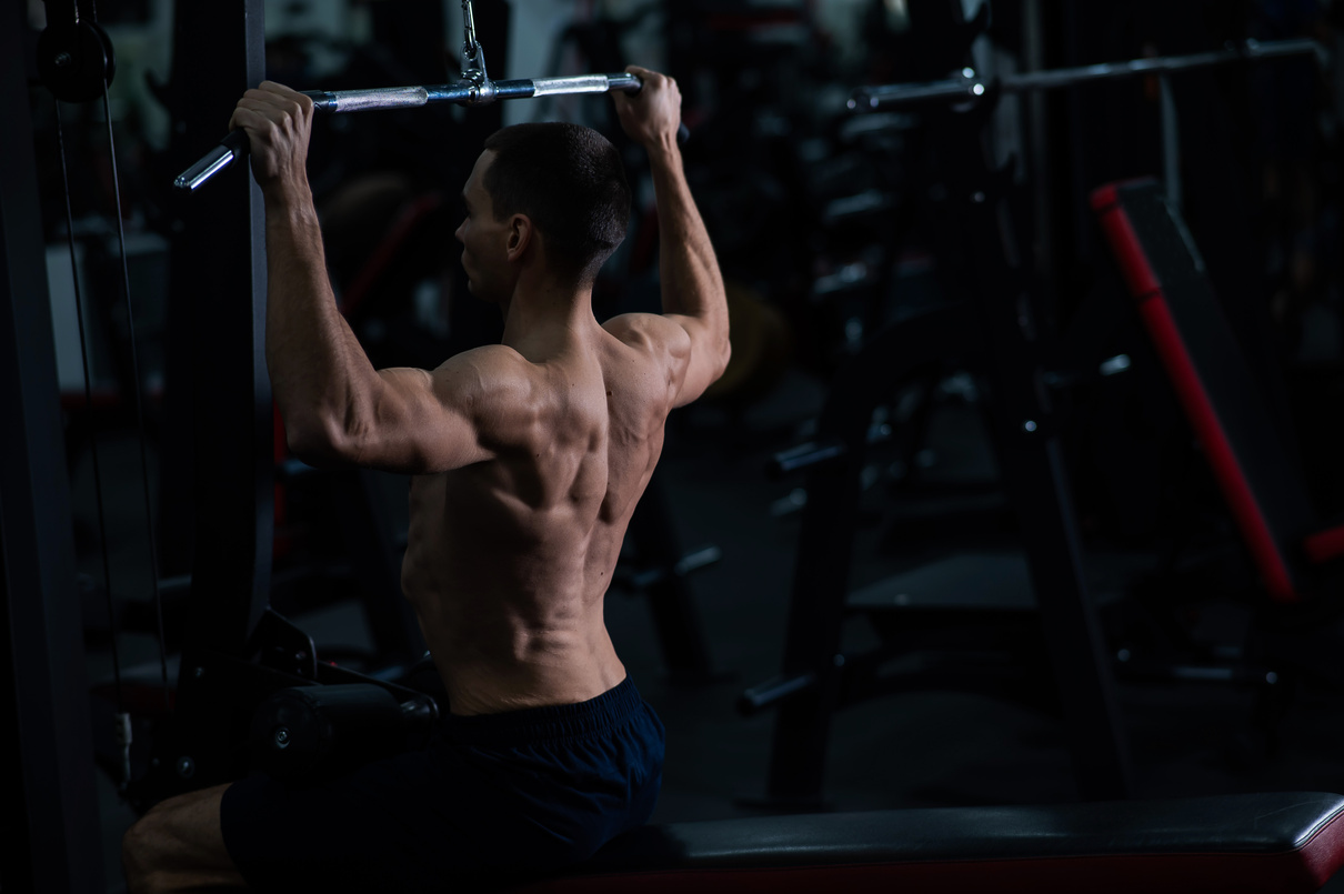 A man does a chest pulldown in the gym.